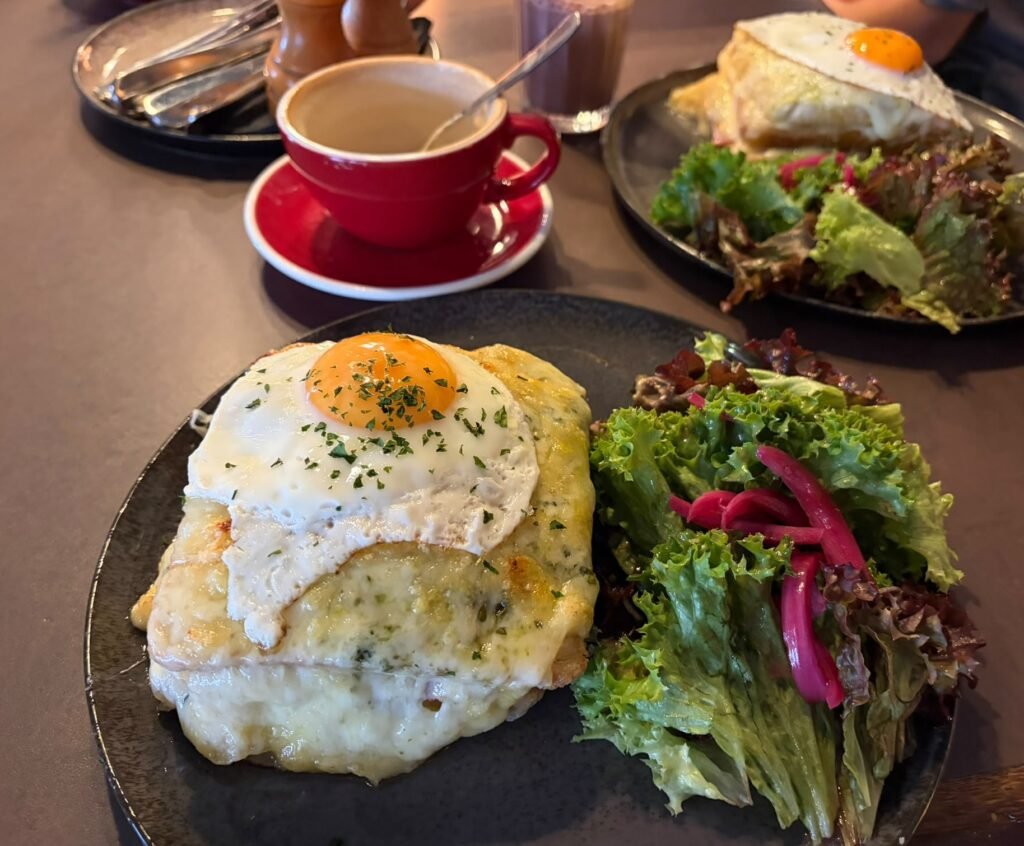 Ein Bild von einer "Croque Madame" am Frühstückstisch, ein Gericht, dass viel Brot und geschmolzener Käse beinhaltet, sowie ein Spiegelei.